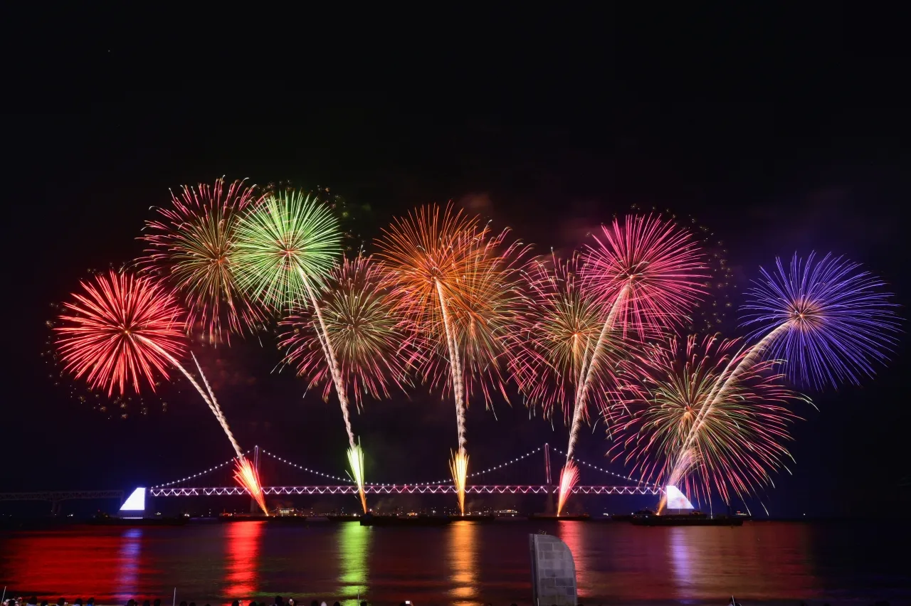 広安里の砂浜から見た釜山花火大会。広安大橋の上に色とりどりの花火が広がり、海面に映っている